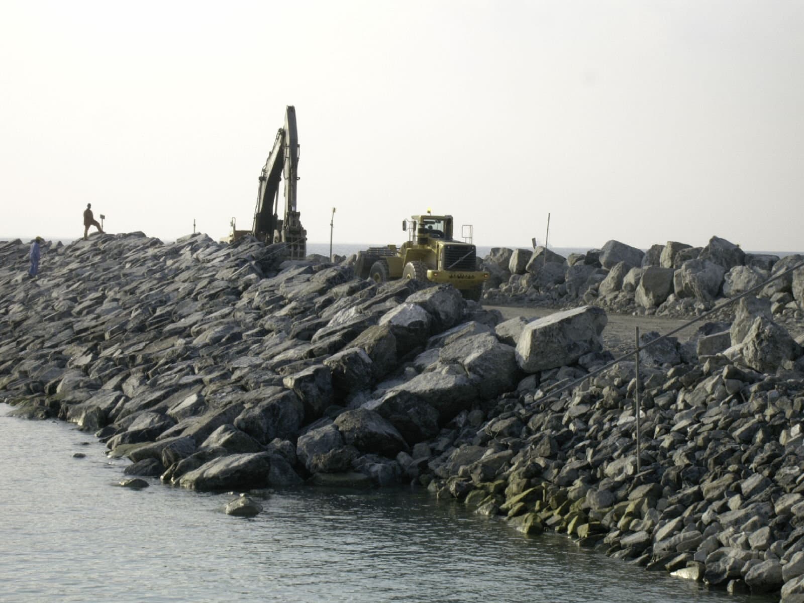 Heavy equipment placing rock along a new shoreline protection structure